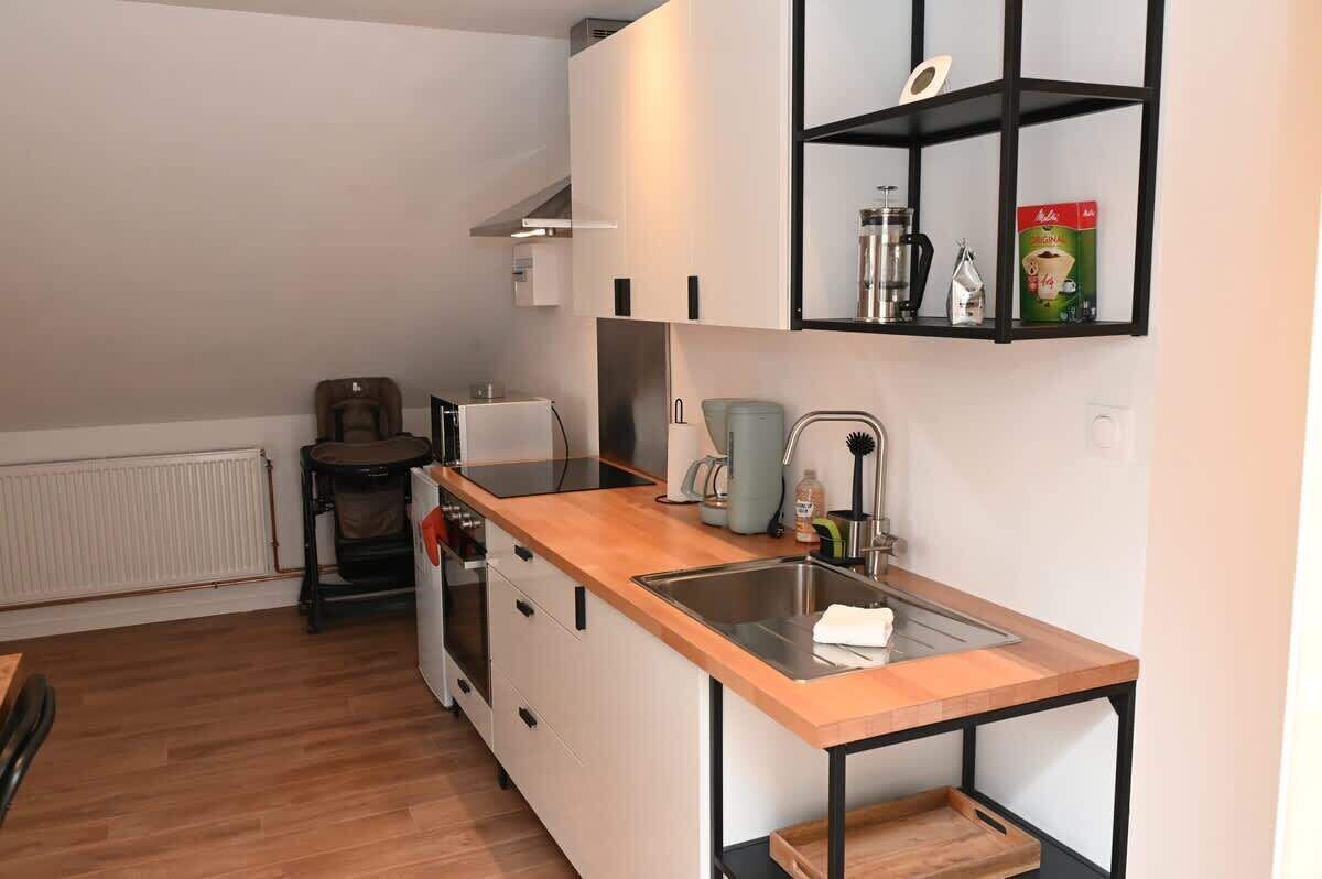 Una cocina compacta con encimera de madera, un lavamanos integrado y un estante negro sobre el lavamanos.