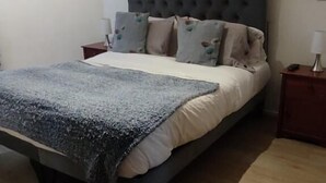 Ein Schlafzimmer mit einem Bett, einem Nachttisch, einer Lampe und einer Deckenleuchte.