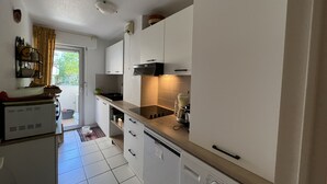 A modern kitchen with white cabinets, a built-in oven, and a washing machine. - Saint-Raphael, near the TGV station, shops, Old Port and beach, large T2 50m2, 4 people, very well equipped and parking (Saint Raphael)