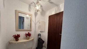 A bathroom with a white vanity, a mirror, a chandelier, and a wooden door. - Saint-Raphael, near the TGV station, shops, Old Port and beach, large T2 50m2, 4 people, very well equipped and parking (Saint Raphael)