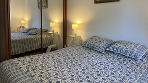 A bedroom with a large mirror, two bedside tables with lamps, a bed with a floral-patterned bedspread, and a framed painting on the wall. - Saint-Raphael, near the TGV station, shops, Old Port and beach, large T2 50m2, 4 people, very well equipped and parking (Saint Raphael)