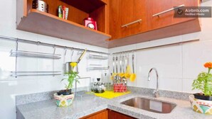 A kitchen with granite countertops, wooden cabinets, a stainless steel sink, and hanging utensils. - Centro wifi vista despejada (Santiago)