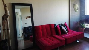 A living room with a red sofa, a large mirror, and a giraffe sculpture. - Centro wifi vista despejada (Santiago)
