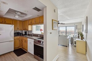 Una cocina moderna con armarios de madera, un refrigerador blanco, un microondas, una estufa y un lavavajillas.