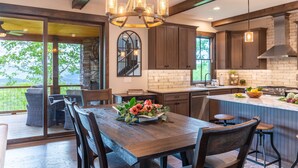 A modern kitchen with a large island, wooden cabinets, and a chandelier.
