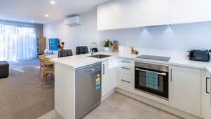 A modern kitchen with white cabinetry, a dishwasher, an oven, and a built-in stovetop.