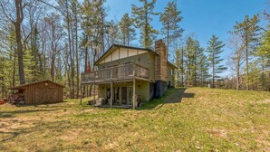 A two-story cabin with a balcony, a covered porch, and a small shed. - Twice Upon A Lake : Summer Retreat for the Whole Family (Curran)