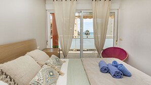 Ein Hotelzimmer mit Bett, Meerblick und einem Balkon mit Stuhl.