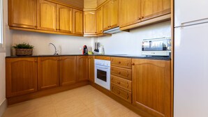 Una cocina con armarios de madera, estufa y microondas.