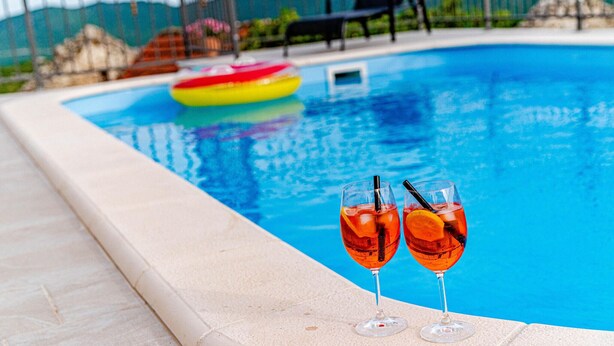 Una piscina amb dos gots de beguda de color taronja al voltant.