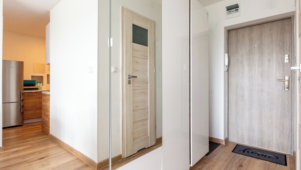 Una cocina moderna con refrigerador integrado, armarios de madera y una encimera con lavamanos.