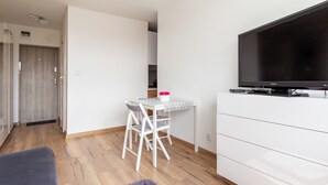 Una sala de estar moderna con una televisión de pantalla plana, una mesa de comedor con sillas, un sofá y un aparador blanco.