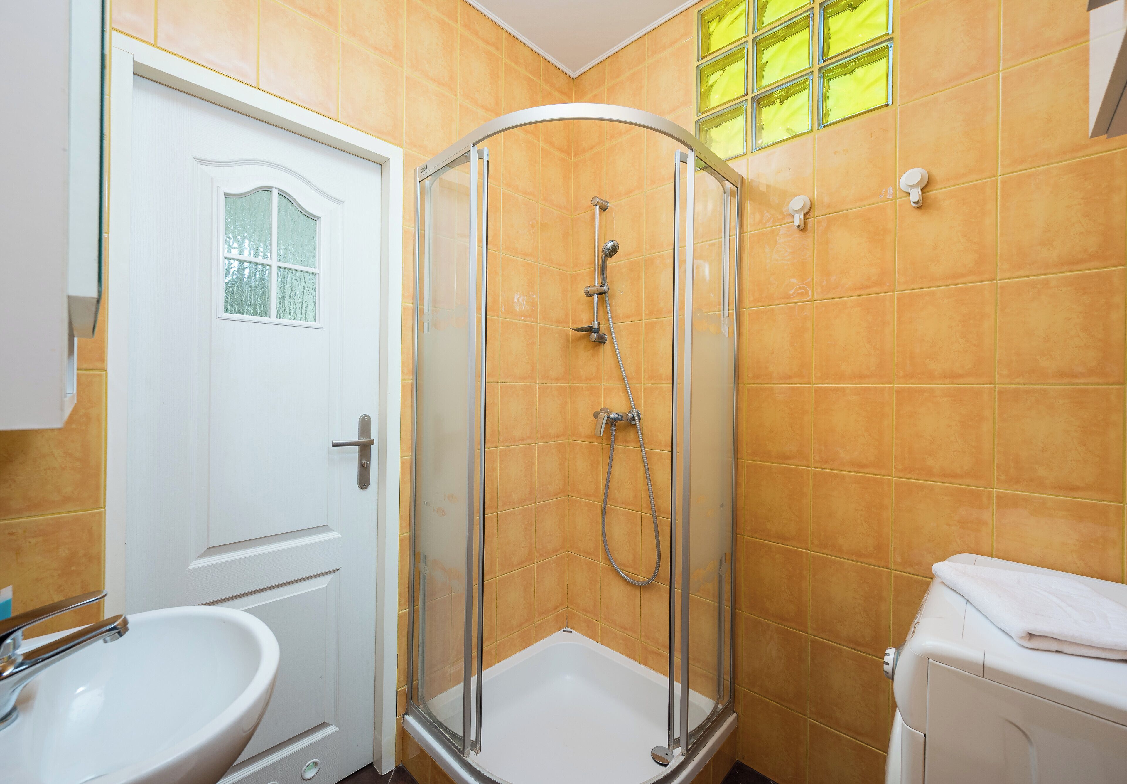 A bathroom with a shower enclosure, a sink, and a toilet.