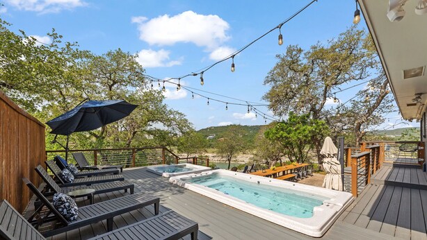 Una terraza con sillones de descanso, un jacuzzi y luces de cuerda.
