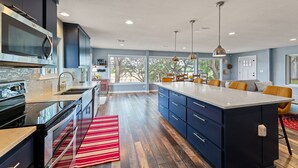 Una cocina moderna con armarios azul oscuro, una isla grande y un tapete a rayas rojas.