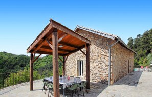 Guests can dine al fresco under a pergola, surrounded by a stone pathway and a metal railing.