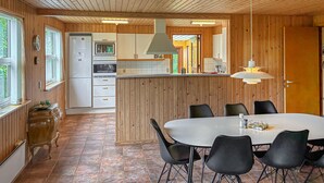 A modern kitchen with wooden paneling, a central island, and a dining area with black chairs. - Awesome home in Væggerløse with WiFi (Væggerløse)