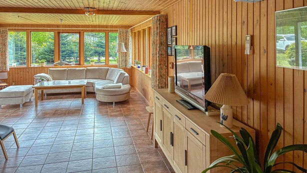 A cozy living room with a sectional sofa, a TV, and a wooden interior. - Awesome home in Væggerløse with WiFi (Væggerløse)