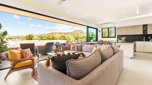 A modern living room with a large sofa, armchairs, and a dining area.