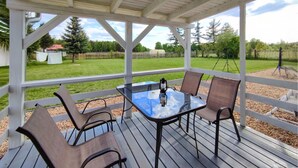 A covered outdoor patio with a glass table and four chairs.