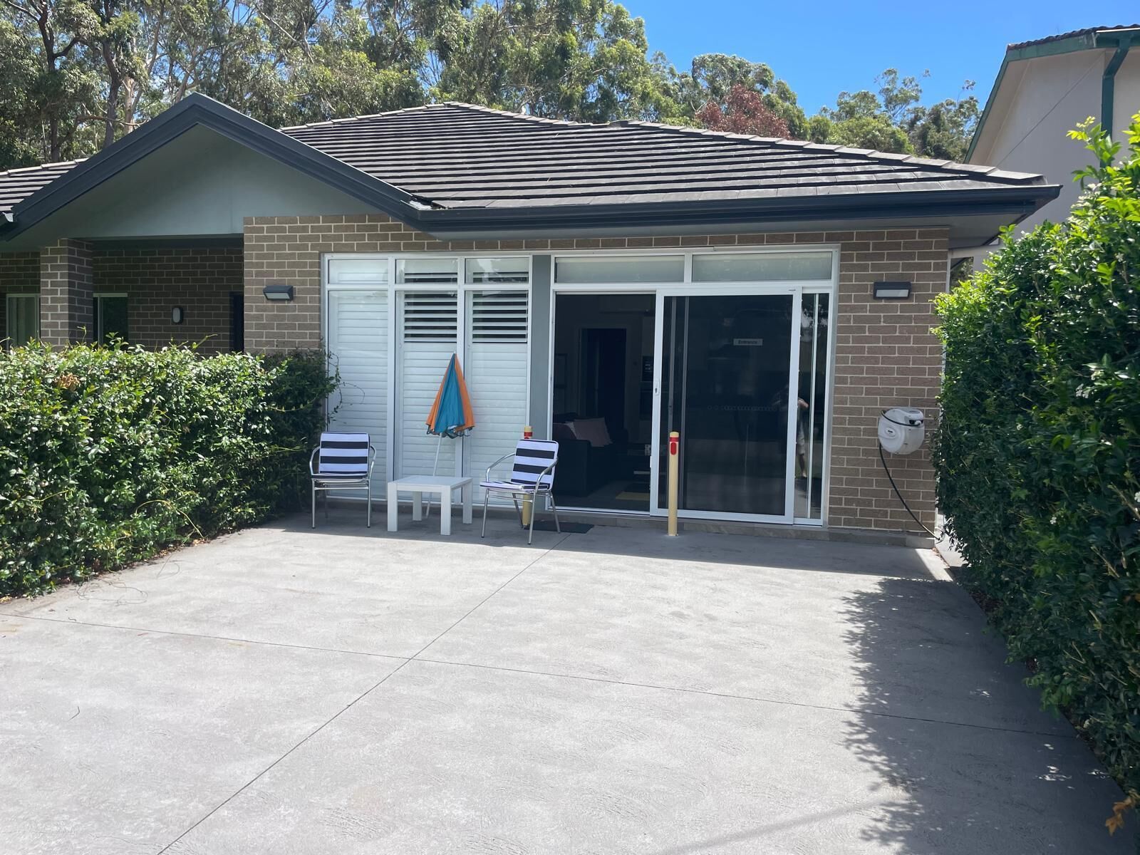 A single-story house with a brick exterior, a tiled roof, and a sliding glass door entrance.