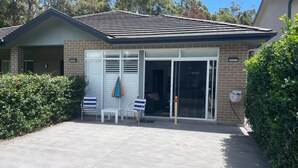 A single-story house with a brick exterior, a tiled roof, and a sliding glass door entrance. - 
Serene Getaway (Callala Beach)