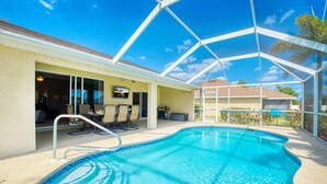 A covered swimming pool with a glass enclosure, adjacent to a building with a patio area and outdoor seating. - VILLA SALTY ESCAPE - HEATED POOL | FAMILY FRIENDLY | BOAT RENTAL + TOURS VOUCHER INCL. (Cape Coral)