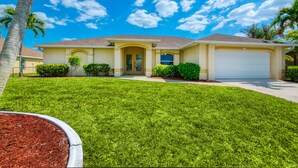 A single-story house with a front yard, a garage, and a well-maintained lawn. - VILLA SALTY ESCAPE - HEATED POOL | FAMILY FRIENDLY | BOAT RENTAL + TOURS VOUCHER INCL. (Cape Coral)