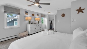 A bedroom with a large bed, a ceiling fan, a dresser with lamps, and a closet. - 2Blocks 2Beach | Free Coffee | Linens+Towels | AC (Belmar)