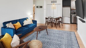 Un salon moderne avec un canapé bleu, une table basse en bois et un tapis à motifs.
