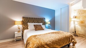 Un dormitorio moderno con una cama grande, dos mesitas de noche con lámparas y una pared de piedra decorativa.