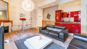 Una sala moderna con una mesa de comedor de vidrio, un sofá de cuero negro y una mesa de centro blanca.