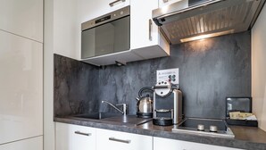 Cocina moderna con electrodomésticos de acero inoxidable, un hervidor y una cafetera.