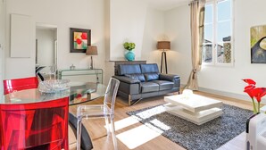 Una sala moderna con una mesa de comedor de vidrio, un sofá gris y una mesa de centro.