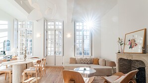 Un salon spacieux doté d’un plancher en bois, d’une cheminée et d’une grande fenêtre.