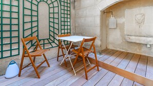 Une pièce avec une table et des chaises en bois, une grille métallique verte sur le mur et une cheminée en pierre.