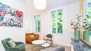 A modern living room with a sofa, two chairs, a coffee table, and a large window with a view of greenery.