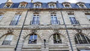 Un bâtiment historique à la façade symétrique, aux encadrements de fenêtres richement décorés et aux éléments en pierre sculptée.