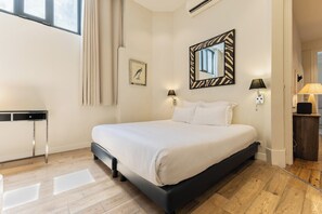 A bedroom with a bed, bedside lamps, a mirror, a picture frame, and a small table.