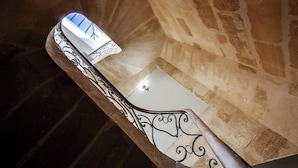 Una escalera con barandales metálicos ornamentados y una bañera blanca al final.