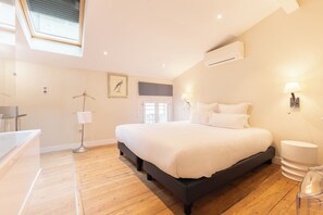 Un dormitorio con una cama grande, un tragaluz, un equipo de aire acondicionado y un baño con bañera.
