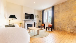 Una sala de estar con chimenea, televisor, sofá y mesa de comedor.