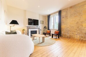 A living room with a fireplace, a television, a sofa, and a dining table.