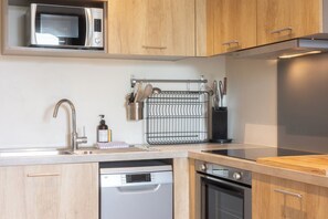 A modern kitchen with wooden cabinets, a microwave, a dishwasher, and a stove. - Maison Ingwë - 4 rooms for 8 persons Place Gambetta (Bordeaux)