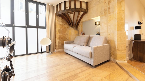 Una habitación con techo de madera, un sofá, una lámpara y un ventanal grande.
