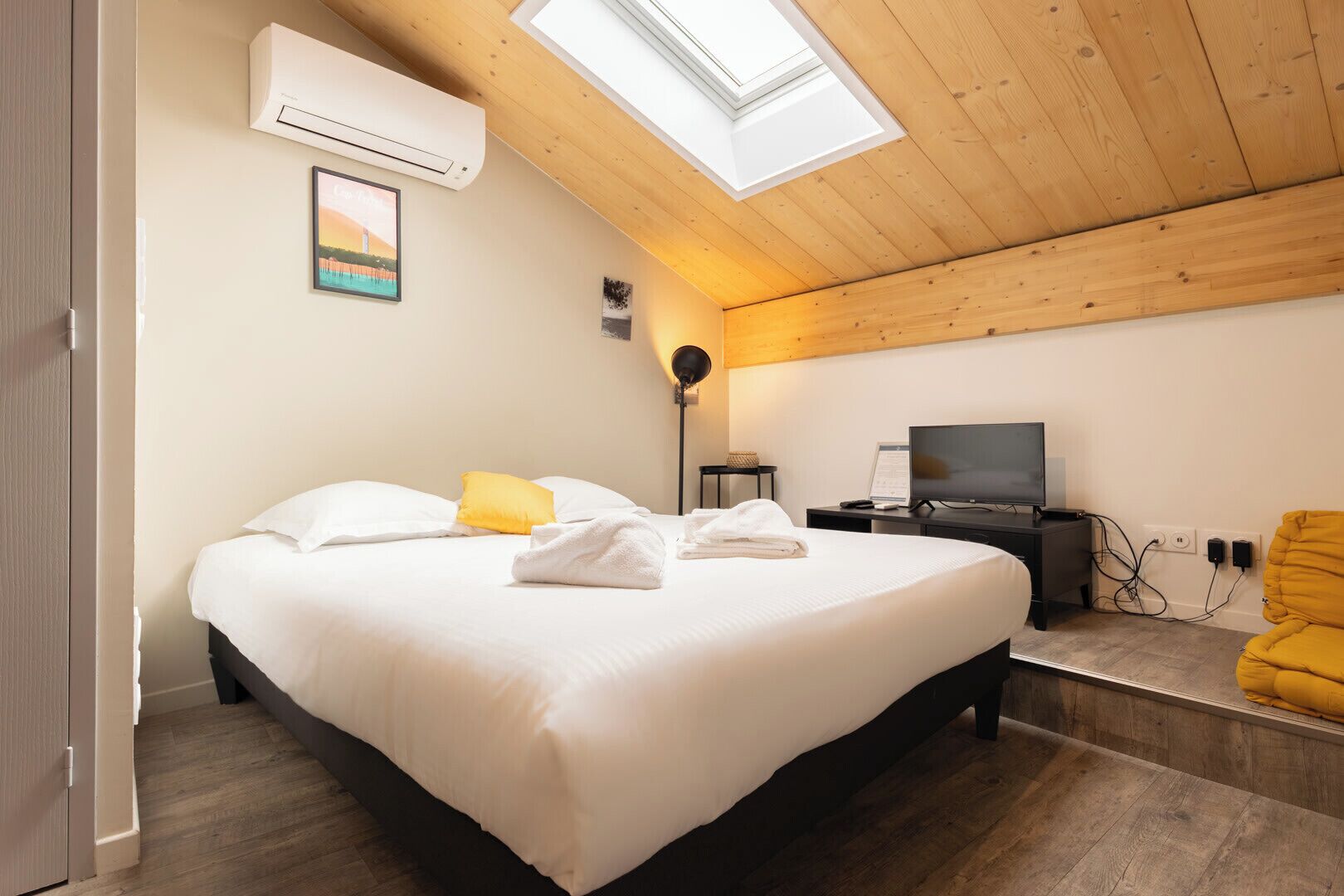 Een slaapkamer met een bed, een televisie, een bureau en een stoel.