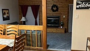 A wooden dining area with a table and chairs, a fireplace, and a 'Welcome' sign. - Poconos Dream House (East Stroudsburg)
