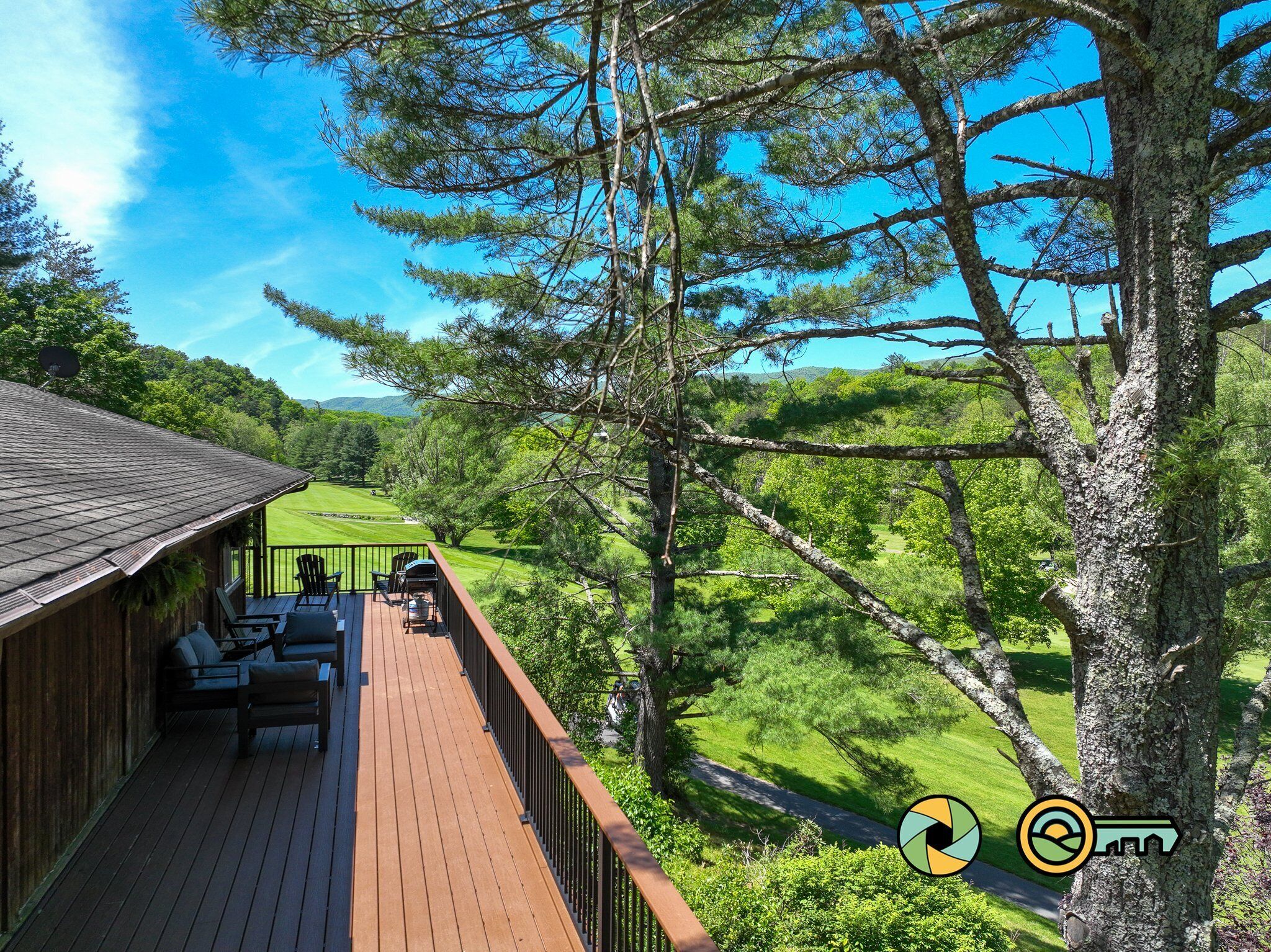 A wooden deck with outdoor seating, overlooking a lush green landscape and a golf course.