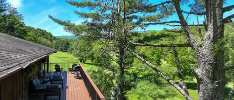 A wooden deck with outdoor seating, overlooking a lush green landscape and a golf course.