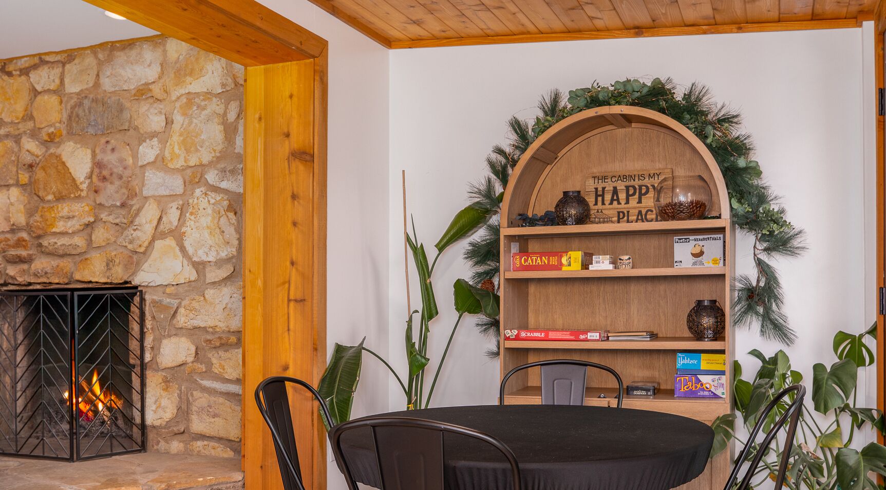 A cozy room with a stone fireplace, a wooden bookshelf, and a round table with chairs.